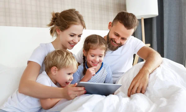 Šťastná rodina se smála s počítačem v posteli doma. hodinky — Stock fotografie