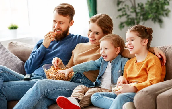 Mutlu, genç ebeveynler ve şirin çocuklar evdeki kanepede oturup patlamış mısır yerken ve hafta sonunun tadını çıkarırken komik filmler izliyorlar.