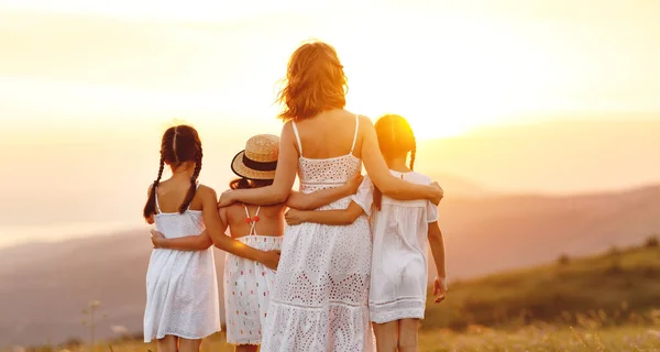 夏の屋外で幸せな家族を見てください 母抱擁子供娘オンSunse — ストック写真