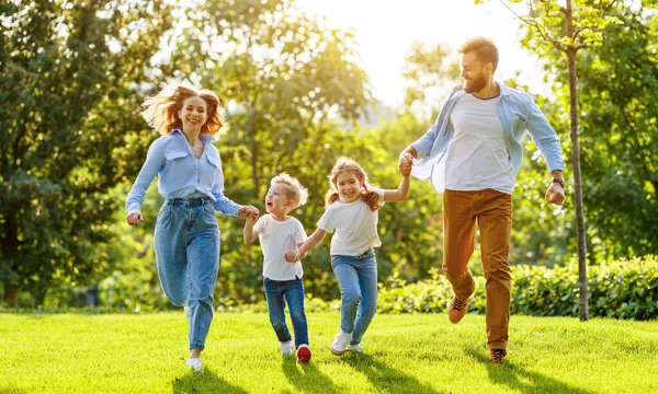 Opgewonden Ouders Kinderen Glimlachen Lopen Hand Hand Camera Groen Gazon — Stockfoto