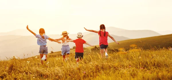 穿着休闲装的 难以辨认的快乐小女孩 在日落时一起在绿地里玩耍 一起跑步 在乡间度过暑假 — 图库照片