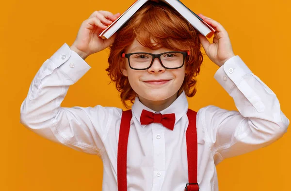 Delizioso Ragazzo Rossiccio Occhiali Sorridente Fotocamera Tiene Libri Sulla Testa — Foto Stock