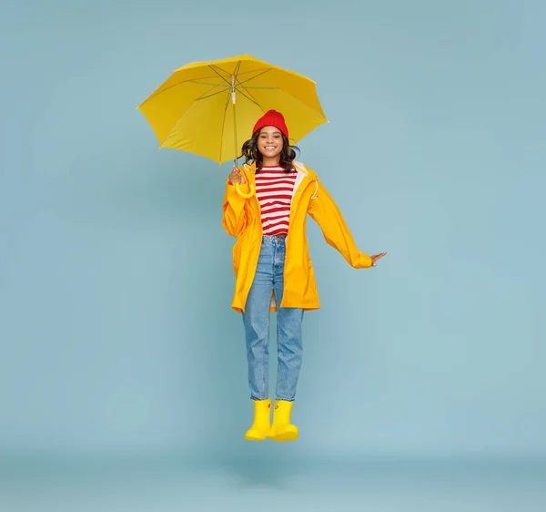 全身幸せな民族の女性でスタイリッシュな衣装を身に着けて傘とジャンプオン青背景色 — ストック写真