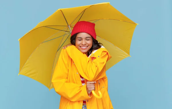 黄色の傘を持つ陽気な民族の女性は笑い 青い背景に雨の秋の日に目を閉じて笑顔 — ストック写真