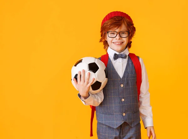 身穿校服 戴着眼镜 对着摄像机笑着 背着足球 背着黄色的背带学习的男孩 — 图库照片