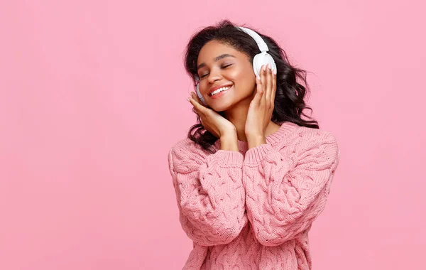 快乐的年轻女性微笑着 在粉色背景音乐中听着好听的音乐 — 图库照片