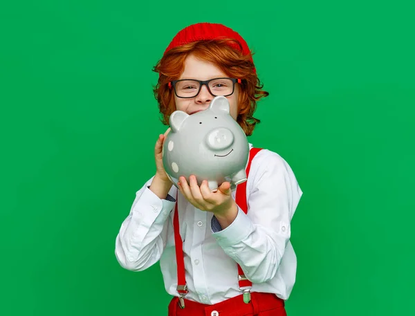 Positiver Ingwerjunge Lässigen Outfit Lacht Und Spart Sparschwein Vor Grünem — Stockfoto