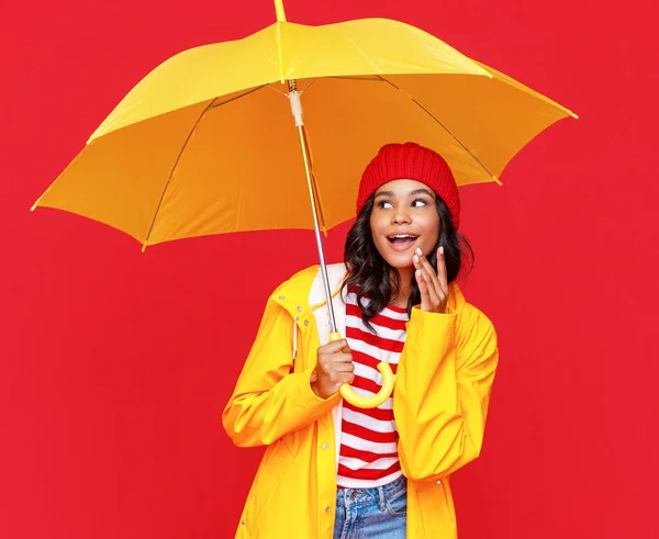 陽気な民族の女性とともに黄色の傘笑顔と上を指して雨の日に対して赤 — ストック写真