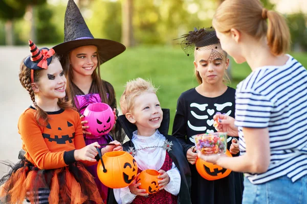 Dorosła Kobieta Daje Słodycze Szczęśliwym Dzieciom Kostiumach Halloween Podczas Imprezy — Zdjęcie stockowe