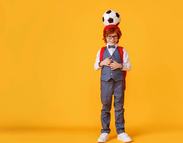 穿着校服 头戴足球的时髦男孩在学习完黄色背风球之后 头上顶着足球 — 图库照片
