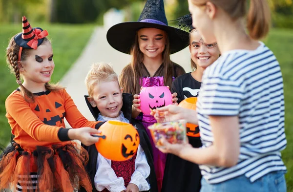 Yetişkin Bir Kadın Cadılar Bayramı Kostümlü Mutlu Çocuklara Şeker Veriyor — Stok fotoğraf
