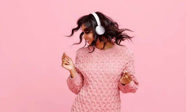 快乐的年轻女性 戴着耳机 一边听音乐 一边用粉红的背景音乐跳舞 — 图库照片