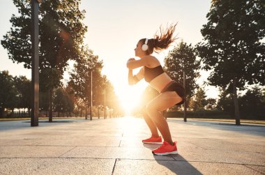 Kulaklıklı genç bir bayan dışarıda spor yapıyor.