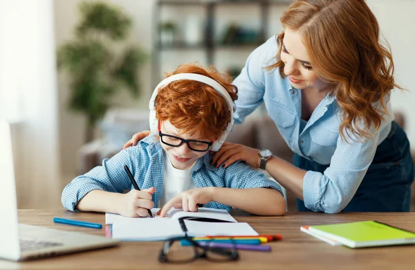 年轻妈妈帮小儿子在眼镜上做作业 一边看着儿子的笔记本 一边在网上学习 — 图库照片