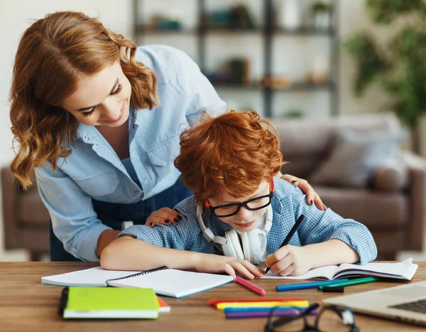 Joven Madre Ayudando Hijo Pequeño Anteojos Con Tarea Mira Cuaderno — Foto de Stock