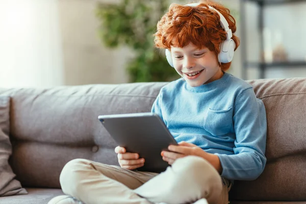 Alegre Pouco Gengibre Menino Fones Ouvido Sorrindo Enquanto Sentado Cruzado — Fotografia de Stock