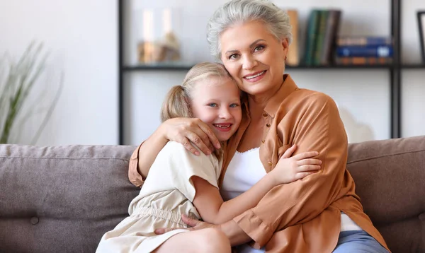 Joyful Little Girl Hugging Happy Grandmother While Sitting Together Sofa — Stock Photo, Image
