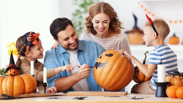 陽気な家族の父親 子供たちは ハロウィーンのお祝いの間に居心地の良いキッチンでテーブルを囲みながら カボチャを作ってジャック ランタンを描きます — ストック写真