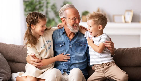 幸せな家族幸せな小さな子供たちは祖父を抱きかかえて笑いながら一緒にソファの上に座って祖父母Da — ストック写真