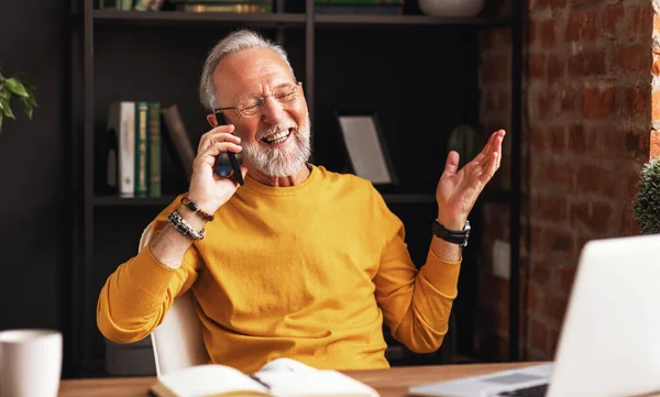 时尚的老人坐在舒适的工作场所的办公桌前 微笑着接听电话 — 图库照片