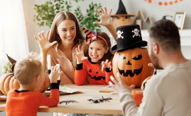 Mutlu ebeveynler ve çocuklar balkabaklı Jack o Lantern evde Cadılar Bayramı kutlamalarında birbirlerine korkunç suratlar yapıyorlar.