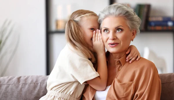 Little Girl Whispering Secret Ear Astonished Elderly Woman While Sitting — Stock Photo, Image