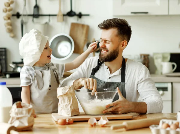 Aşçı Şapkalı Şirin Çocuk Gülen Babanın Yüzüne Hamur Sürerken Mutfağında — Stok fotoğraf