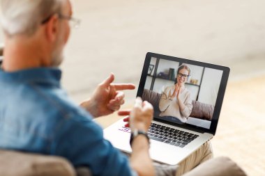 Bulanık yaşlı baba gülen genç bayana fıkra anlatırken evde bilgisayarla video görüşmesi yapıyor.