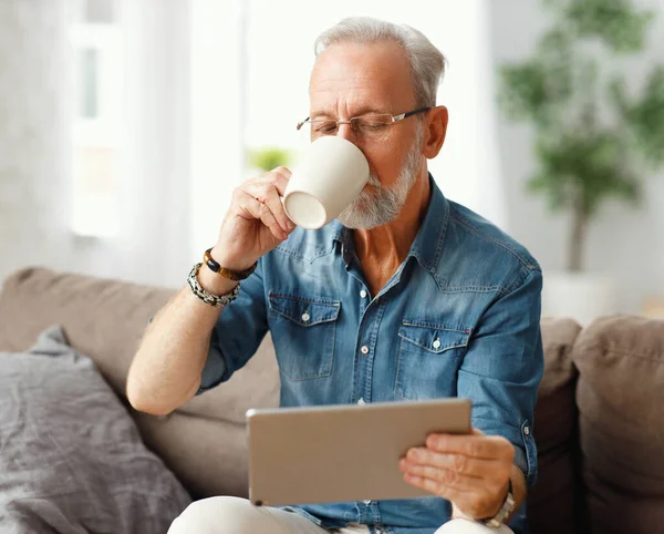 Anciano Masculino Sorbiendo Bebida Caliente Taza Tableta Navegación Mientras Descansa — Foto de Stock
