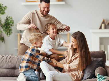 Mutlu aile anne baba ve çocuklar evde kanepede eğleniyorlar.