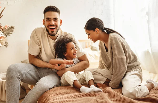 快乐的家庭多民族的母亲 父亲和儿子在卧室里哈哈大笑 挠痒痒 — 图库照片