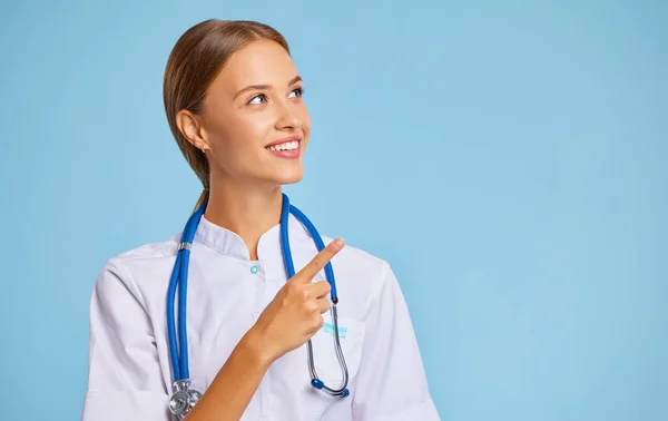 Friendly Woman Doctor Nurse Uniform Smiles Pointing Blank Space White — Stock Photo, Image