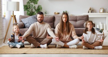 Mutlu sağlıklı aile evde lotus pozisyonunda yoga meditasyonu yapar.