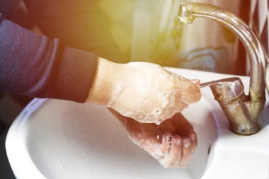 adam su ve güneş etkisi, hijyen kavramı ile musluk altında sabunla el yıkama.