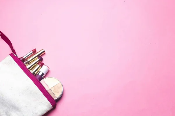 makyaj çantası ve değişik renkli ruj içeren toz pembe bir arka plan üzerinde yüz