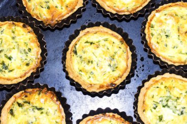 siyah plaka üzerinde mini metal formlardaki ev yapımı kiş pasta pişmiş