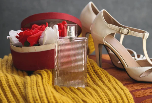 used bottle perfume  above color mustard winter scarf decorated and white, red flowers in box and white heel. marriage concept