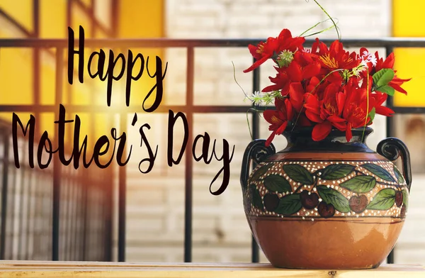 beautiful red flowers on clay vase with cherry fruit painting above wood table and happy mother\'s day concept