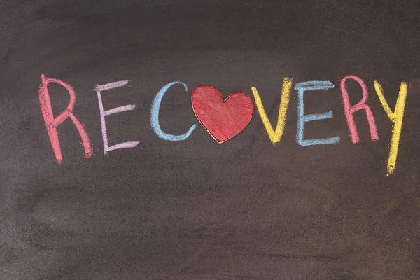 recovery phrase handwritten on blackboard with heart symbol instead of O, hand holding green chalk