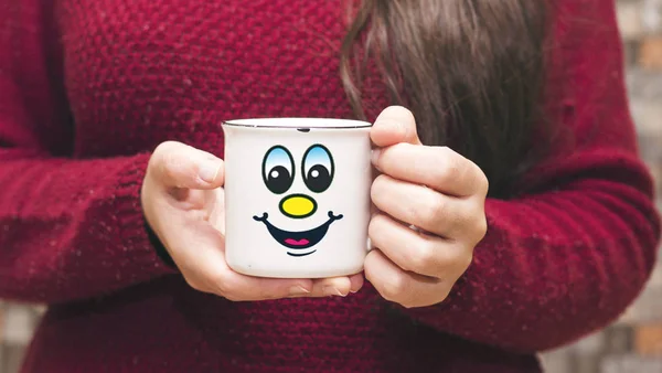 closeup woman with a long hair holding a cup coffee with happy cartoon face