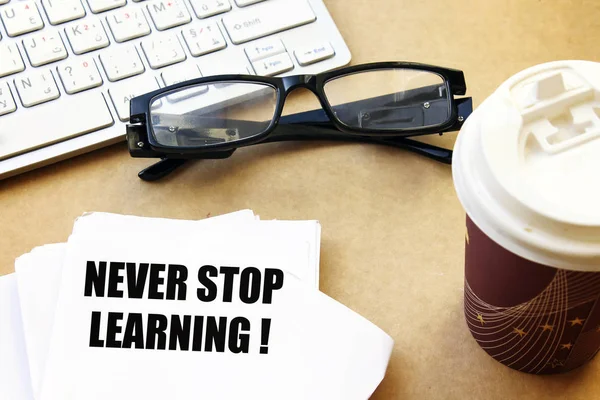 never stop learning ! on white paper with coffee and eyeglasses, white keyboard
