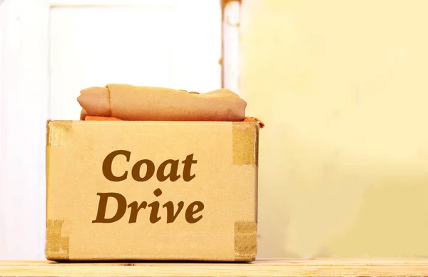 clothes in carton box on wood table for donation, coat drive concept