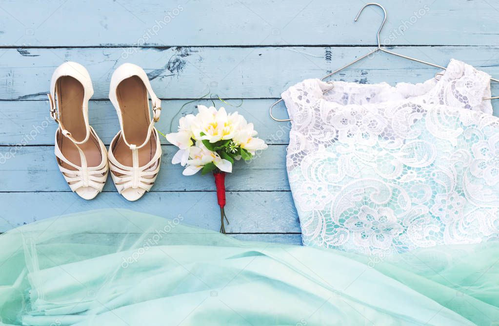 top view of wedding bouquet and dress, white heels  on wooden  blue tabletop