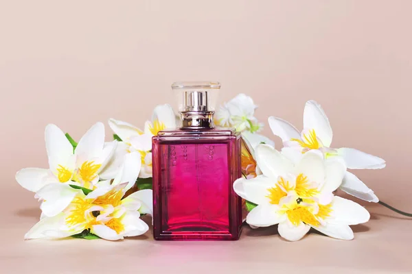 ピンクの背景に白い花を持つヴィンテージのボトルの香水 — ストック写真