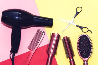 Renkli arka planda izole profesyonel kuaförlük araçları ve siyah kurutma makinesi