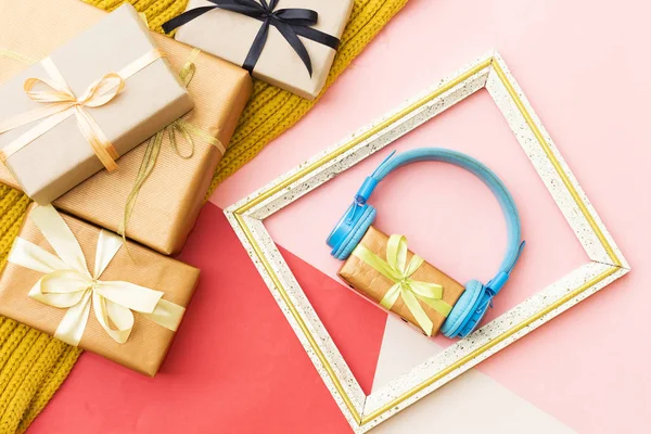 Christmas music gift concept. Headphones and gift boxes and wooden photo frame on colorful background