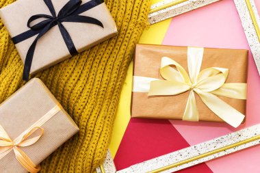 kırmızı, sarı ve pembe arka planda ahşap çerçeve fotoğraf ve kış eşarp ile üç renkli kağıt üzerinde üç dikdörtgen hediyeler kutusu