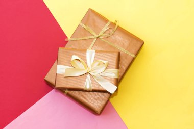 Üç renkli kağıt üzerinde iki dikdörtgen hediye kutusu: kırmızı, sarı ve pembe