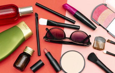 temel tozu ve üç renk allık, ruj ve maskara fırça, şişe parfüm ve şampuan pembe ve kırmızı kağıt 