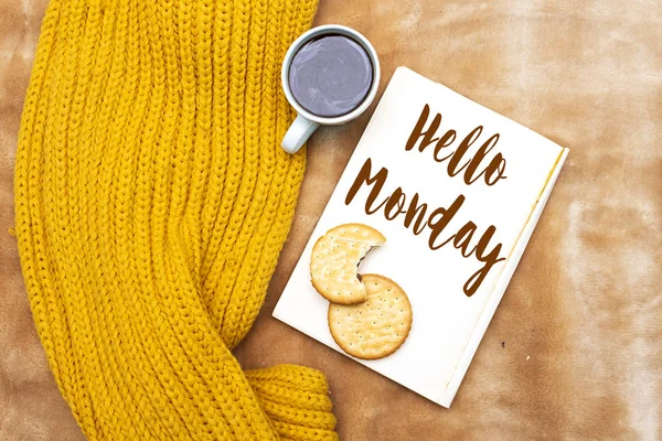 winter concept, hello monday on book with scarf and cup coffee, chocolate cookies